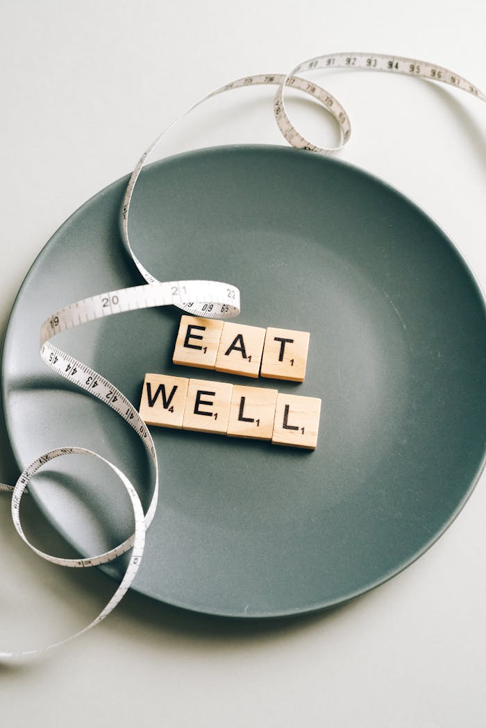 Mastering the First Impression: Your intriguing post title goes here Creative photo of 'Eat Well' letter tiles on a plate with measuring tape, symbolizing balanced nutrition.