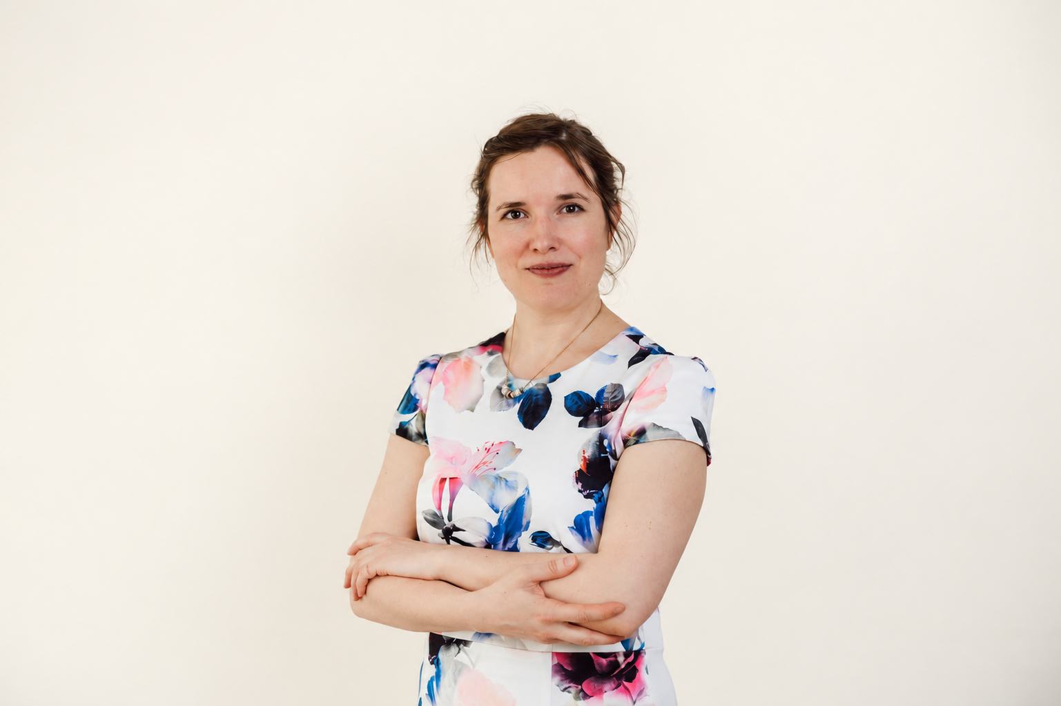 Nele seisab heledal taustal, käed risti ees.